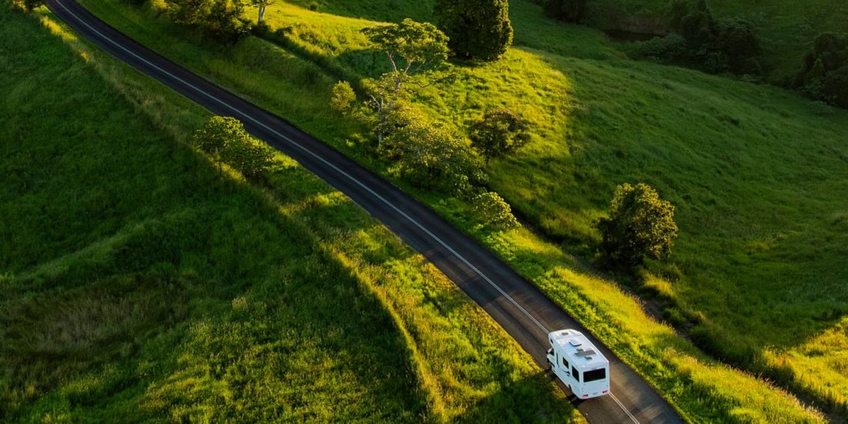 Aerial view of a motorhome on a country road through green hills