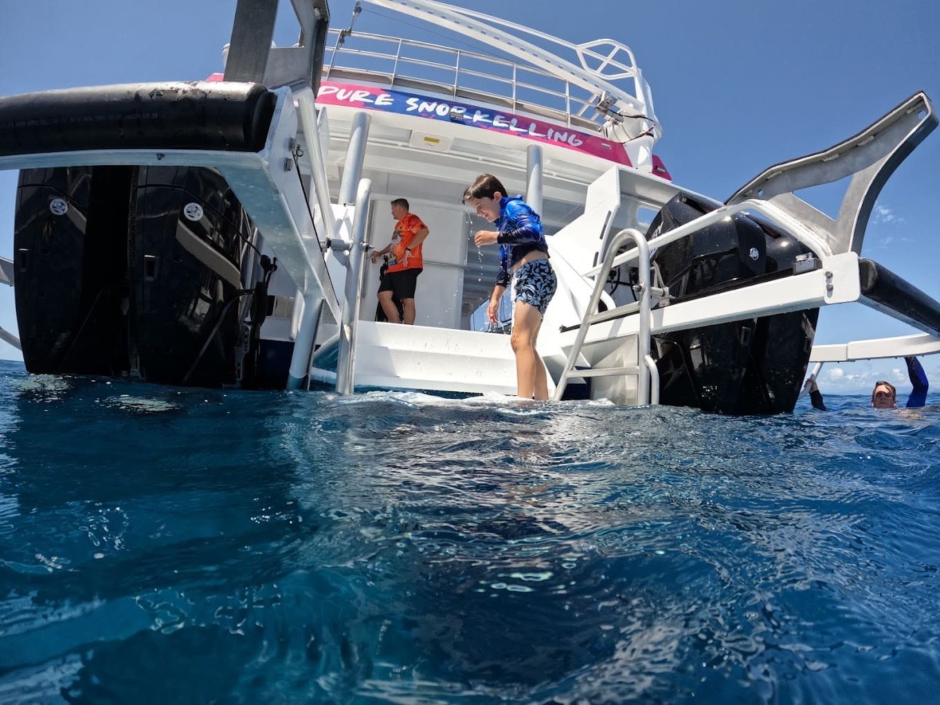 Guests boarding from the rear platform of the Pure Snorkelling vessel