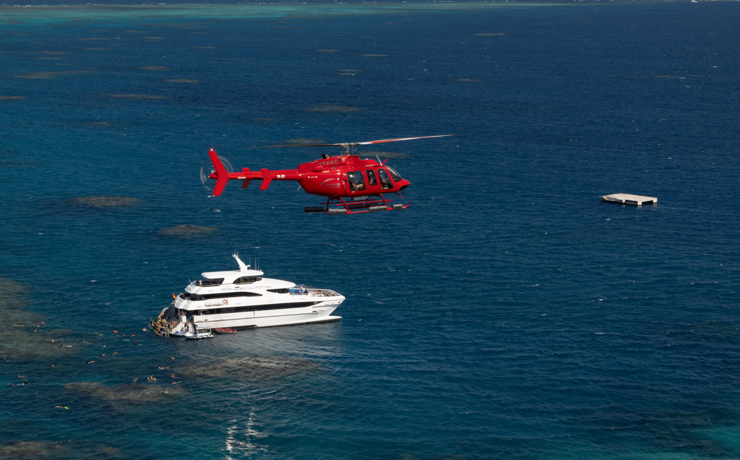 Red helicopter over superyacht