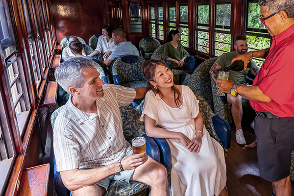 Guests seated in the Gold Class carriage of the Kuranda Scenic Railway being served refreshments