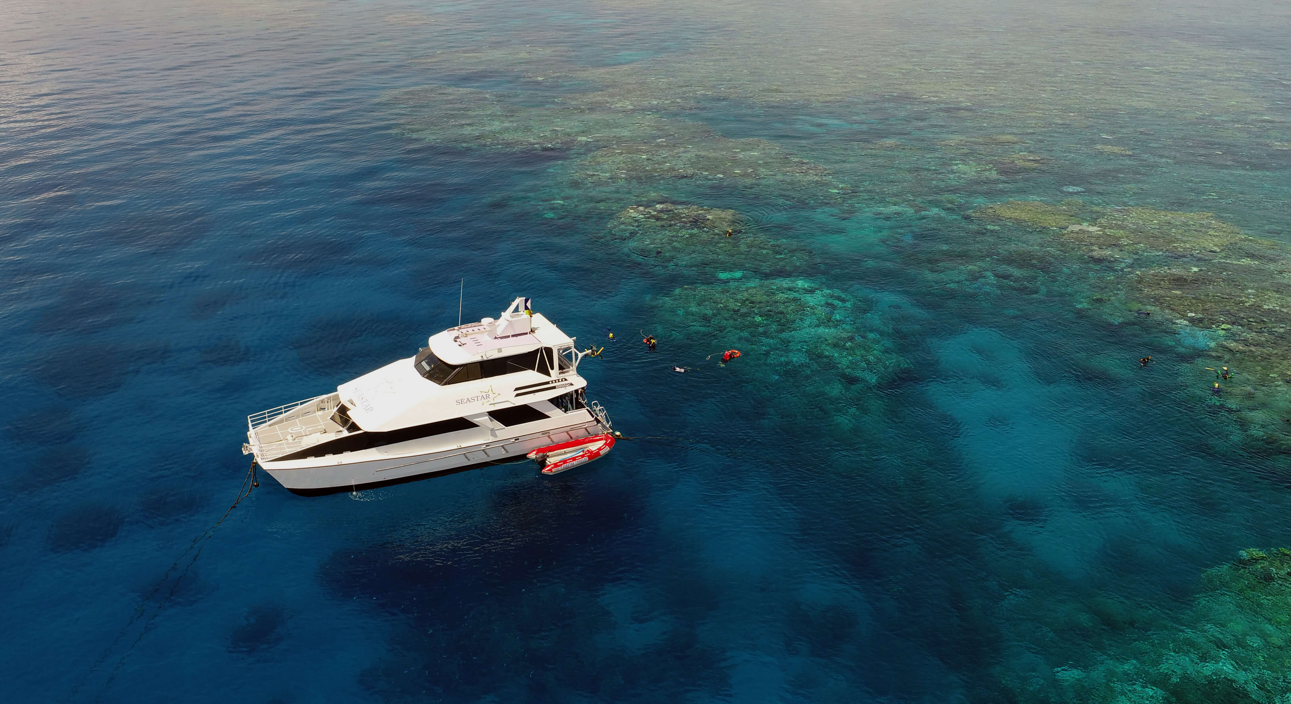 Reef tour boat moored at the outer Great Barrier Reef off Cairns with snorkellers in the water